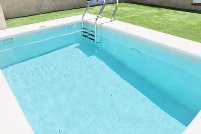 a blue swimming pool with a ladder in it at Chalet del Sultan in Conil de la Frontera