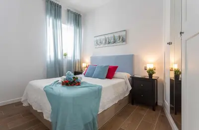 a bedroom with a bed and a table with flowers on it at Doña Blanca Centro Diseño Minimalista in Jerez de la Frontera