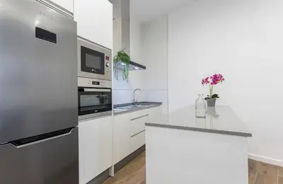 a white kitchen with a refrigerator and a counter at Doña Blanca Centro Diseño Minimalista in Jerez de la Frontera