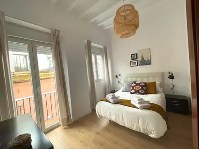a white bedroom with a bed and a balcony at La Galería de Botica in Cádiz