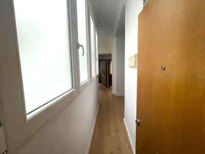 an empty hallway with a window and a wooden door at La Galería de Botica in Cádiz