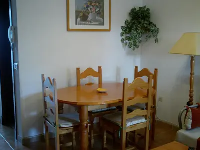 a dining room table with four chairs and a table and a lamp at Primera línea de playa casita adosada in Chiclana de la Frontera