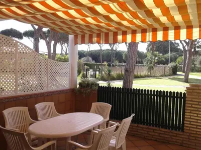 a table and chairs under an umbrella on a patio at Primera línea de playa casita adosada in Chiclana de la Frontera