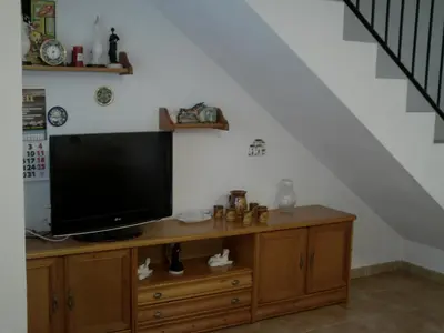 a television on a wooden cabinet under a staircase at Primera línea de playa casita adosada in Chiclana de la Frontera