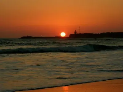 a sunset on a beach with the ocean and the sun at EL ATARDECER in Conil de la Frontera