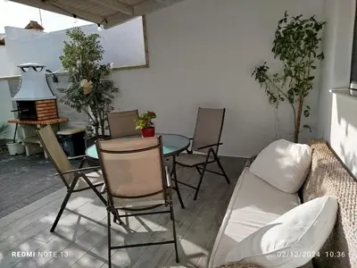 a patio with two chairs and a table and a palm tree at EL ATARDECER in Conil de la Frontera