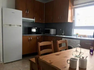 a kitchen with a wooden table and a white refrigerator at Apartamento sureño in Cádiz