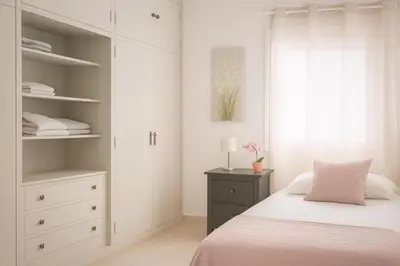 a white bedroom with a bed and a dresser at Apartamento sureño in Cádiz