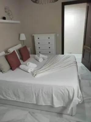 a bedroom with a white bed with red pillows at Idalia 19 Atico in Sanlúcar de Barrameda