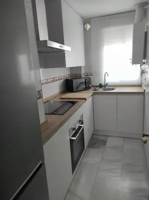 a small kitchen with white cabinets and a sink at Idalia 19 Atico in Sanlúcar de Barrameda