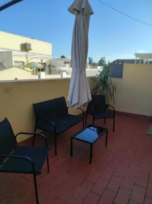 a patio with chairs and an umbrella and a table at Idalia 19 Atico in Sanlúcar de Barrameda