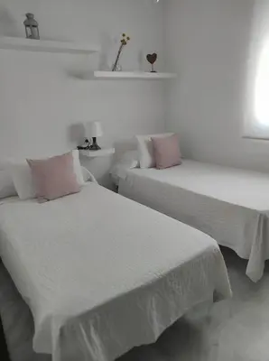 two beds in a room with white walls and pink pillows at Idalia 19 Atico in Sanlúcar de Barrameda