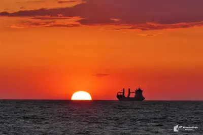 a boat in the ocean with a sunset at Chipiona Santuario de Regla Playa Bajo A in Chipiona