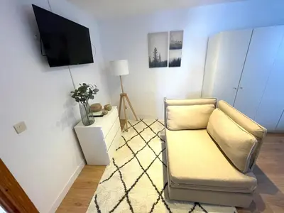 a living room with a chair and a flat screen tv at El Ático de Botica in Cádiz