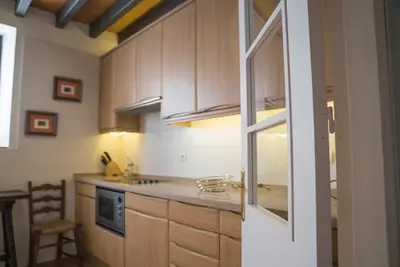 a kitchen with wooden cabinets and a counter top at Loft en casa Palacio Mergelina Parking gratis in Sanlúcar de Barrameda