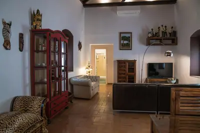 a living room with a couch a chair and a television at Loft en casa Palacio Mergelina Parking gratis in Sanlúcar de Barrameda