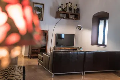 a living room with a couch and a television at Loft en casa Palacio Mergelina Parking gratis in Sanlúcar de Barrameda