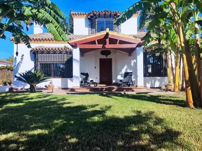 a house with a porch and a yard with palm trees at The Magic House in El Puerto de Santa María