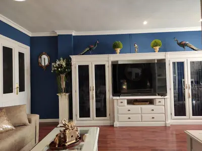 a living room with blue walls and a large tv at Caprichos in Jerez de la Frontera