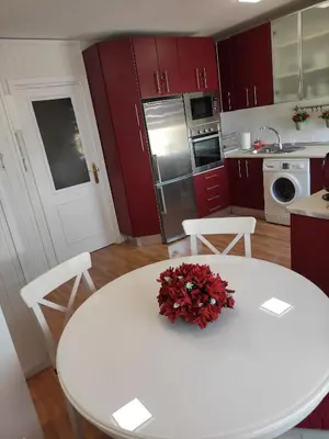 a kitchen with a white table and red cabinets at Caprichos in Jerez de la Frontera