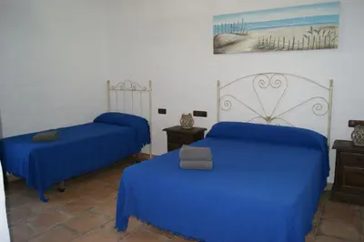 two beds in a room with blue sheets at EL ALAZAN in Chiclana de la Frontera