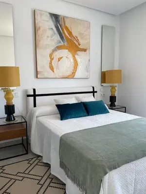a bedroom with a bed with two lamps and a painting at LyriosHomes Luxury Costa Ballena Beach in Chipiona