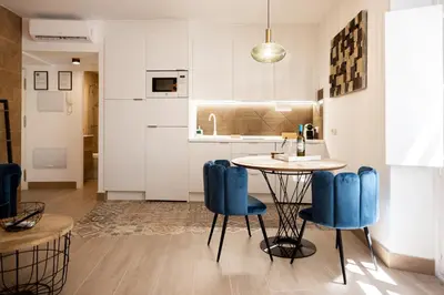 a kitchen with a table and blue chairs at La Terraza del Populo Little Apartments in Cádiz