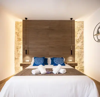 a bedroom with a large white bed with blue pillows at La Terraza del Populo Little Apartments in Cádiz