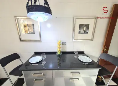 a dining room table with two chairs and a chandelier at Casa Hermosilla con piscina by Sanlúcar Housing in Sanlúcar de Barrameda