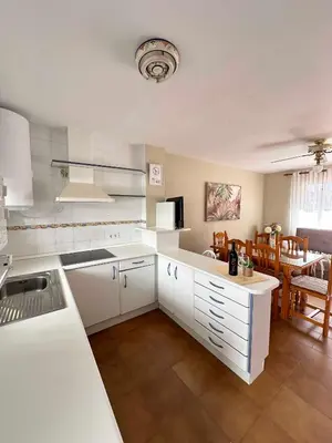 a kitchen with white cabinets and a dining room at Dúplex Playa Sol Ostra in Chiclana de la Frontera