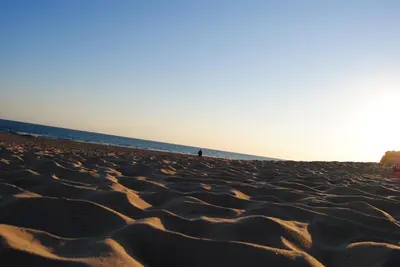a person standing on a sandy beach next to the ocean at Dúplex Playa Sol Ostra in Chiclana de la Frontera