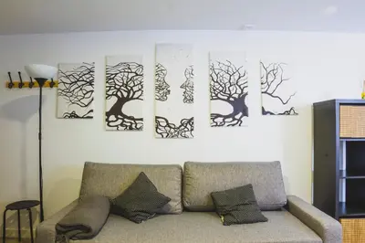 a living room with a couch against a wall with tree paintings at CDZ - Botica in Cádiz