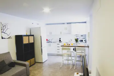 a kitchen with a black refrigerator and a table with stools at CDZ - Botica in Cádiz