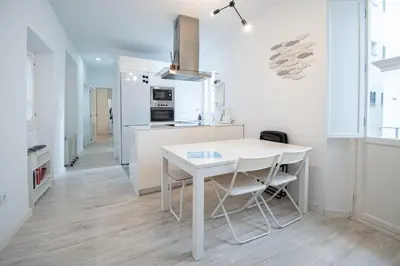 a white kitchen with a white table and chairs at Apartamento Las Lectoras de Cadiz in Cádiz