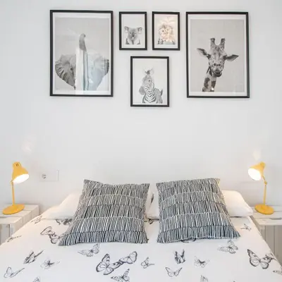 a white bedroom with framed pictures on the wall at Apartamento Las Lectoras de Cadiz in Cádiz
