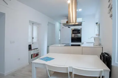 a white kitchen with a white table and chairs at Apartamento Las Lectoras de Cadiz in Cádiz