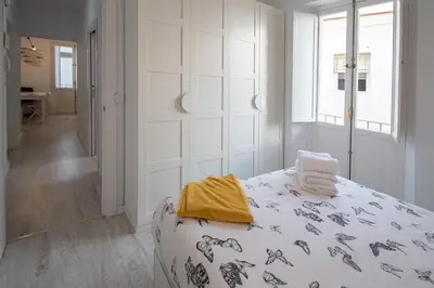 a white bedroom with a bed with a yellow towel on it at Apartamento Las Lectoras de Cadiz in Cádiz