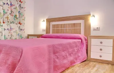 a pink bed with a wooden headboard in a bedroom at Chalet Piedra in Conil de la Frontera