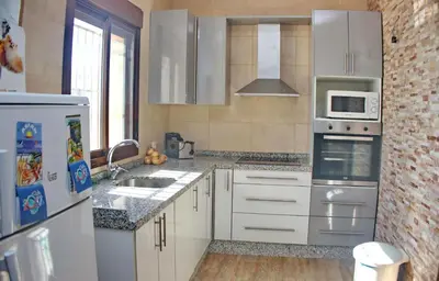 a kitchen with white cabinets and a stove top oven at Chalet Piedra in Conil de la Frontera