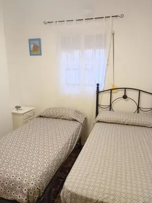 two beds in a bedroom with a window at Apartamento Marina de la bahía in Puerto Real