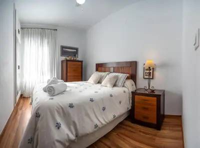 a bedroom with a large bed and a wooden floor at Valdelagrana Sunset Apartment in El Puerto de Santa María