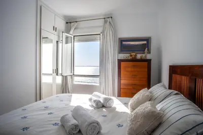 a bedroom with a bed with pillows and a window at Valdelagrana Sunset Apartment in El Puerto de Santa María