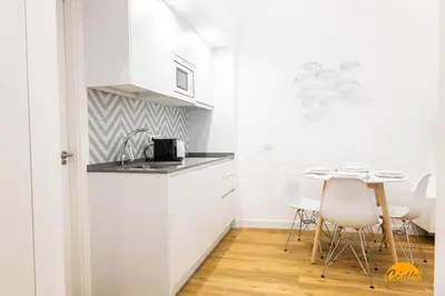 a white kitchen with a table and chairs at Estudio Gaviota by Cadiz Time in Cádiz