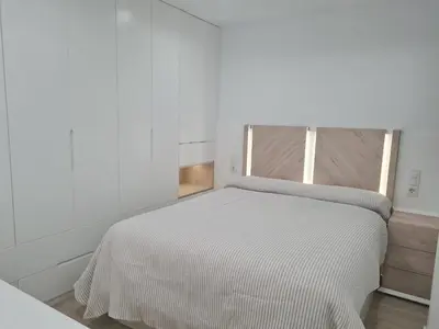 a bedroom with a white bed with a wooden headboard at Casa Viento de Levante in Cádiz
