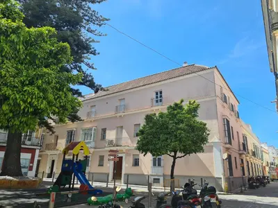 a building with a playground in front of a building at Araucaria Home in Sanlúcar de Barrameda