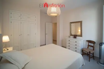 a bedroom with a bed and a chair and a mirror at Araucaria Home in Sanlúcar de Barrameda