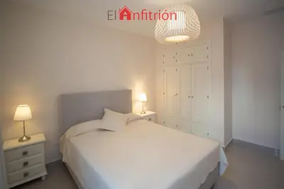a bedroom with a white bed and two night stands at Araucaria Home in Sanlúcar de Barrameda