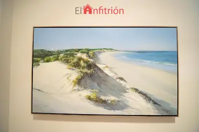 a painting of a beach in a frame on a wall at Araucaria Home in Sanlúcar de Barrameda