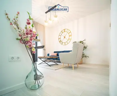 a living room with a vase with flowers in it at Apartamento Diego Benitez in Sanlúcar de Barrameda