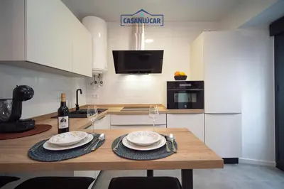 a kitchen with a wooden table with plates and wine glasses at Apartamento Diego Benitez in Sanlúcar de Barrameda